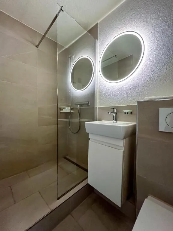 Modernes Badezimmer mit runden Spiegeln und Dusche