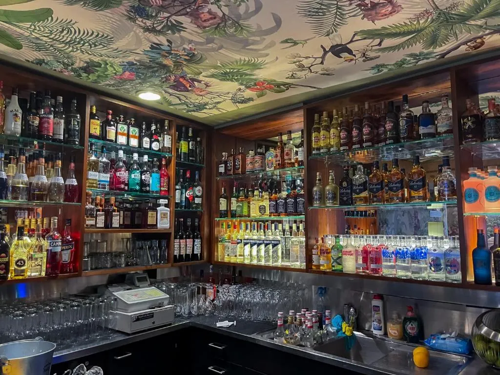 Cocktailbar im stattHotel Zürich mit beleuchtetem Flaschenregal und Blumendecke
