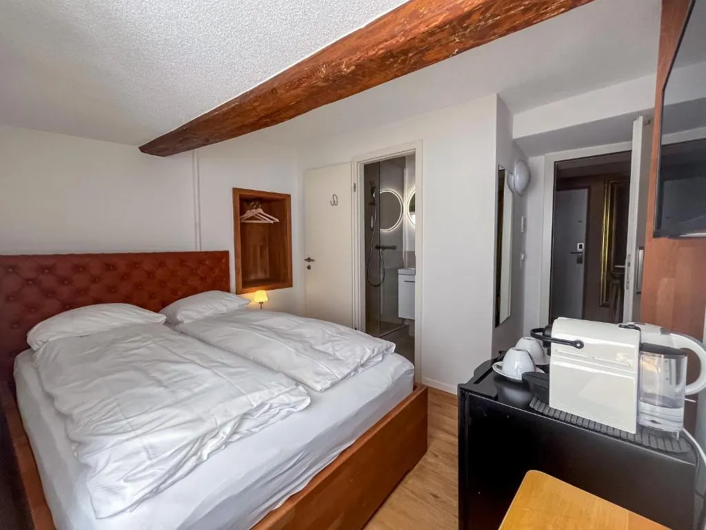 Doppelzimmer mit rotem Samt-Kopfteil und Holzbalken im stattHotel Zürich