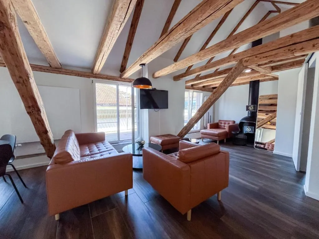 Suite-Lounge mit Ledersofas unter dem historischen Dachstuhl
